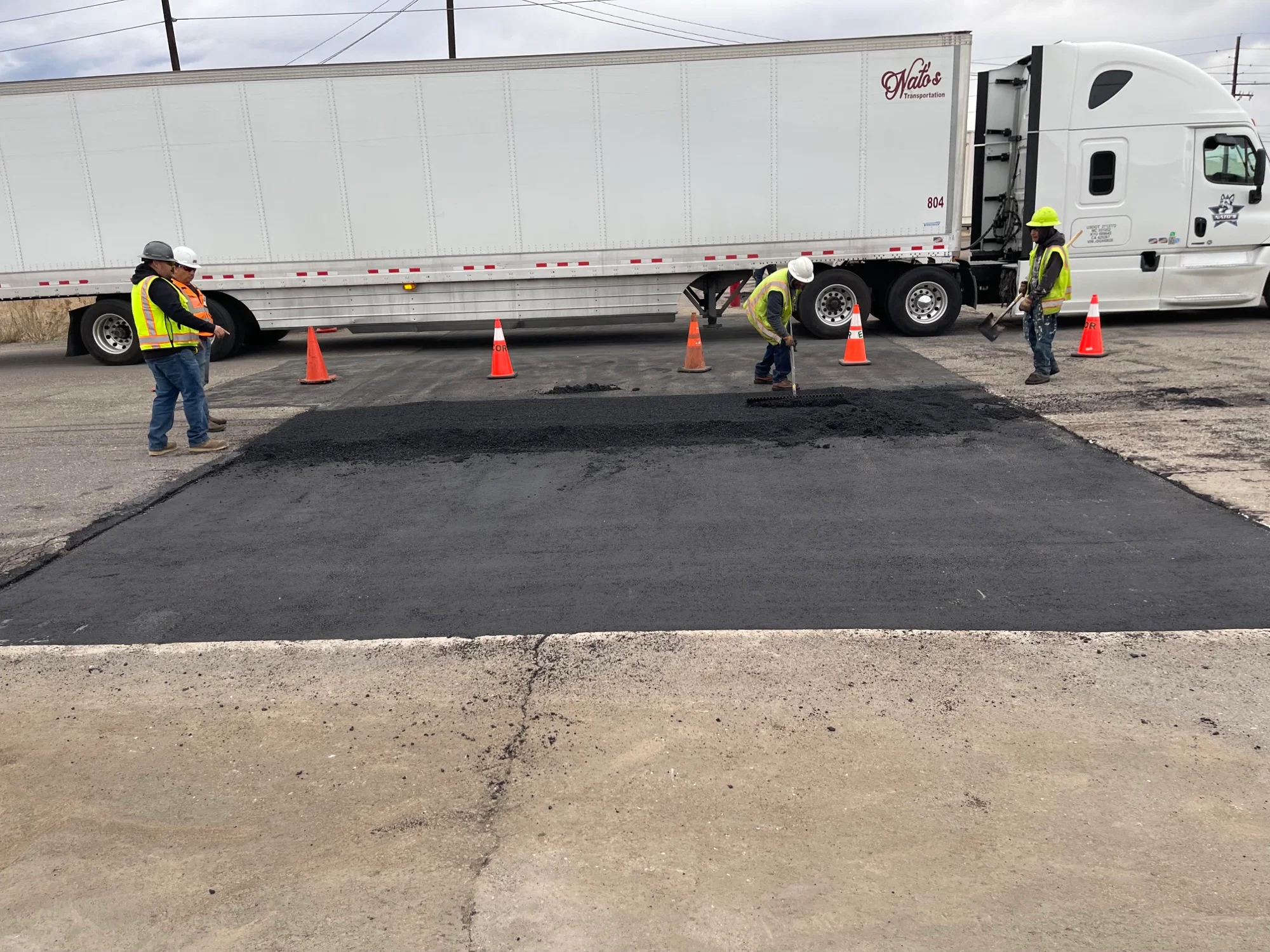 Crew patching an asphalt lot at the Coors Brewing Company facility