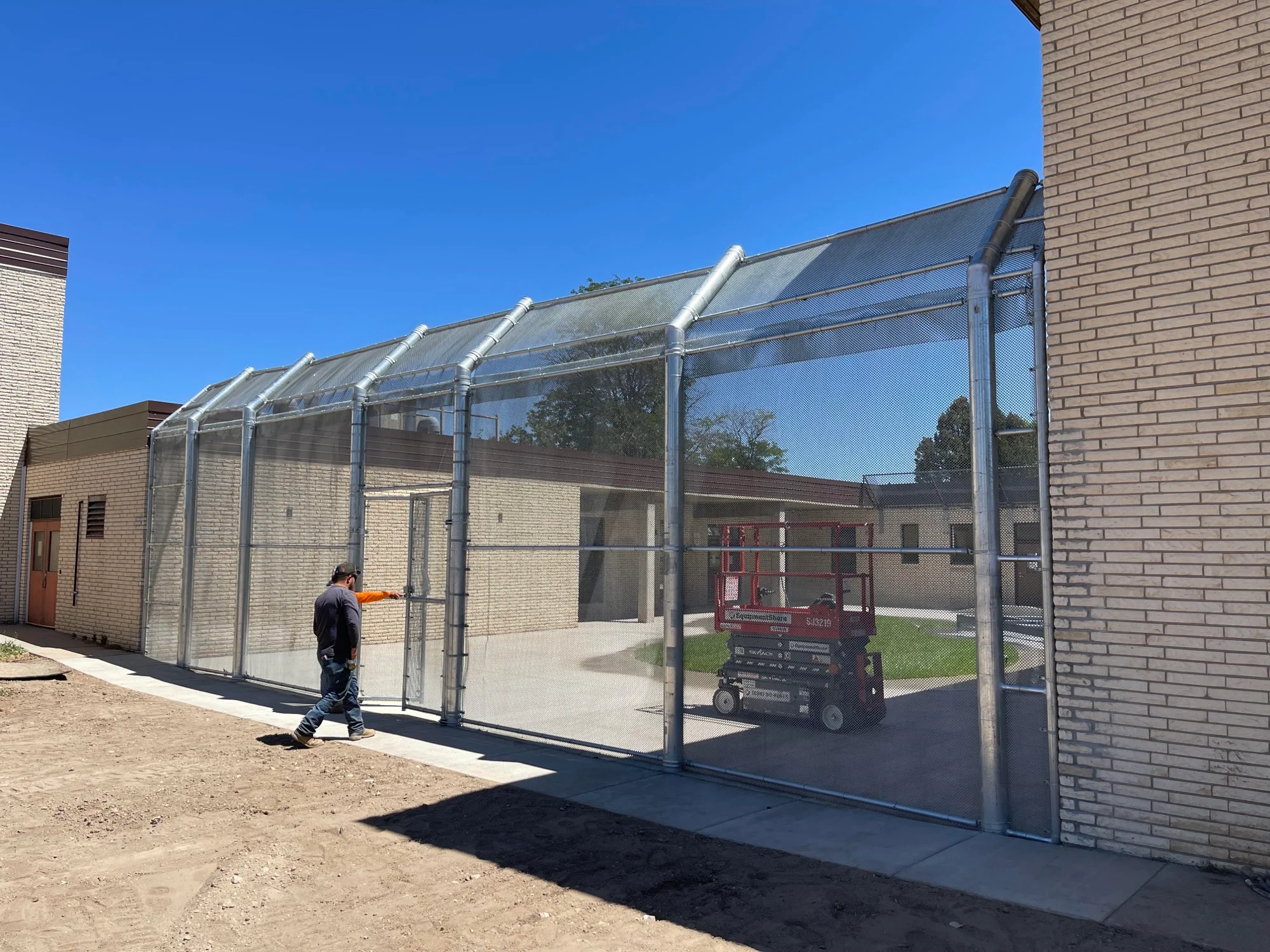 Crew installing a secure fenced walkway enclosure at a CDHS facility