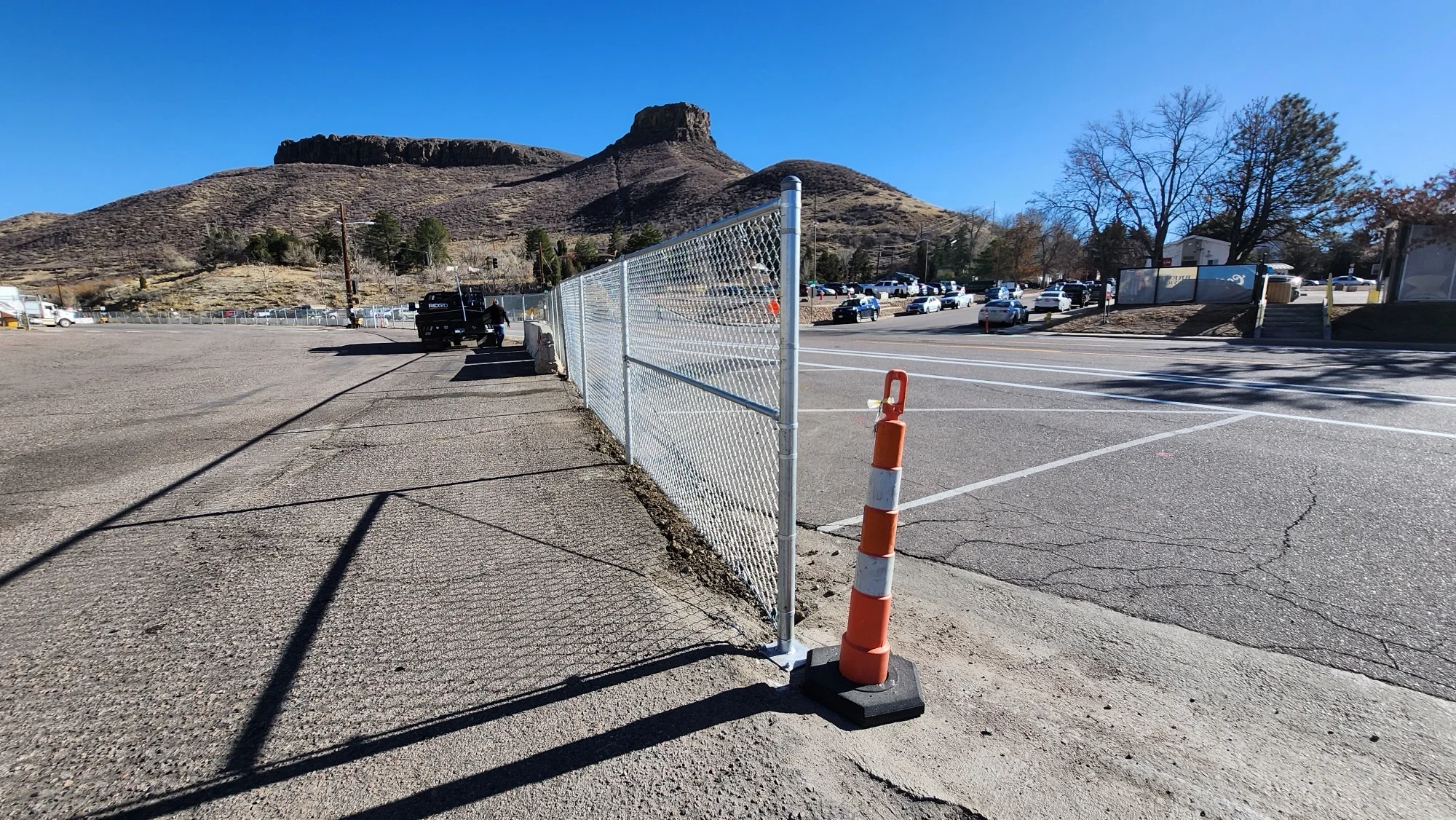 Chain-link fence along a roadway with mountains in the background