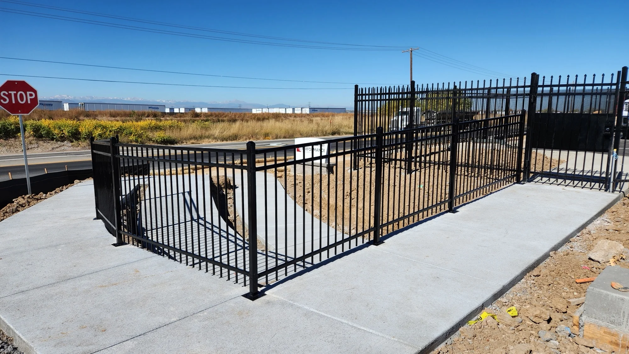 Black ornamental iron fence and gate installed against an open Colorado sky